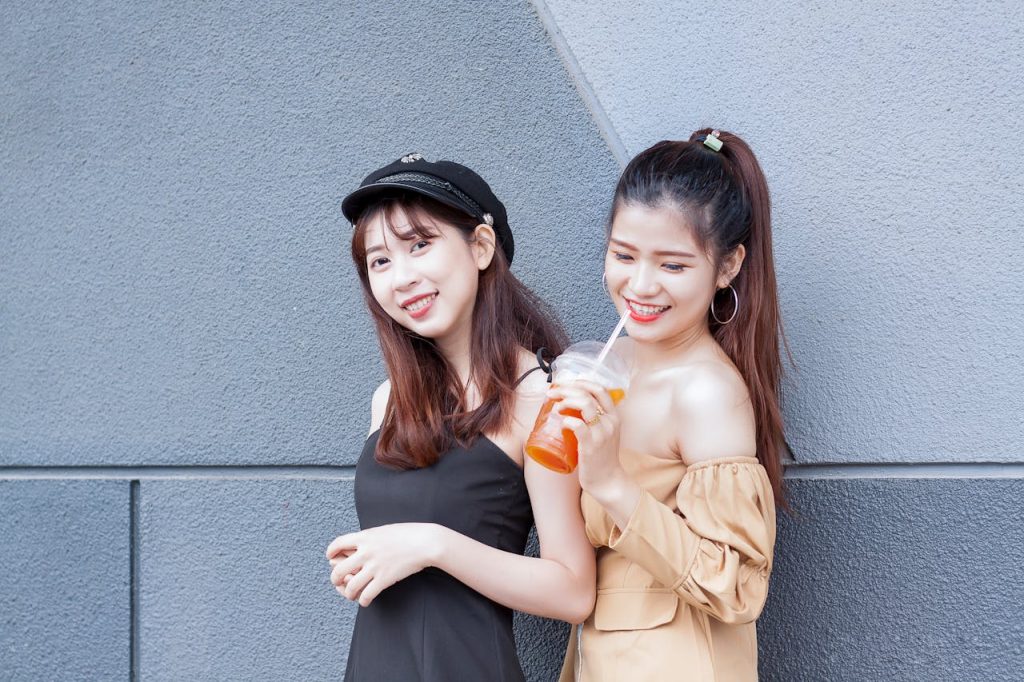 Two fashionable women enjoy a sunny urban day in Ho Chi Minh City with refreshing drinks.